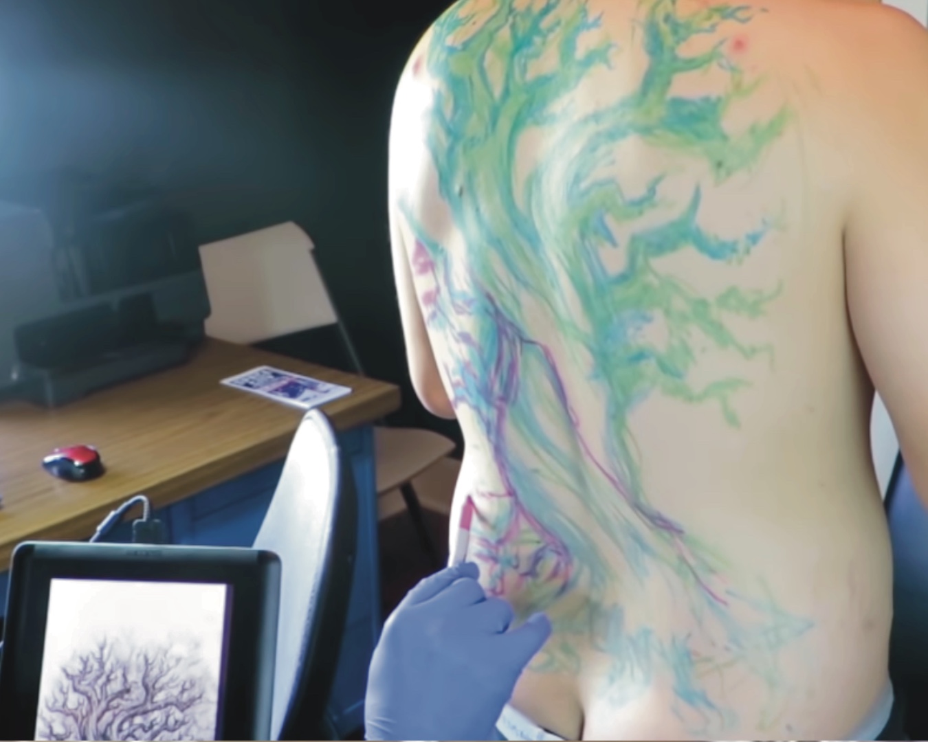 Jake Meeks sculpting a marker drawing of a tree on the client's back