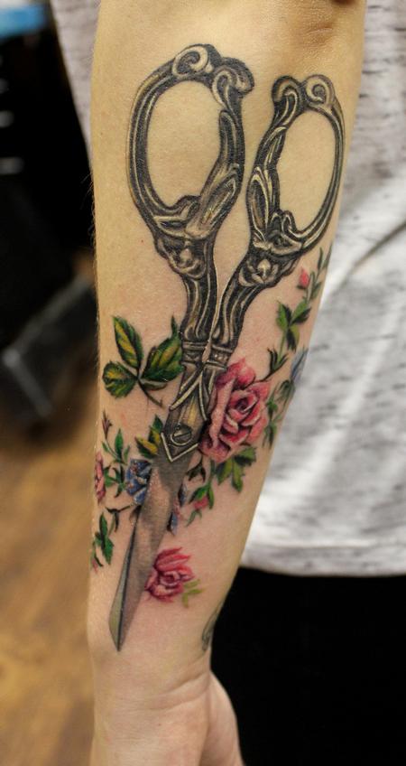 Scissors tattooed on the forearm.